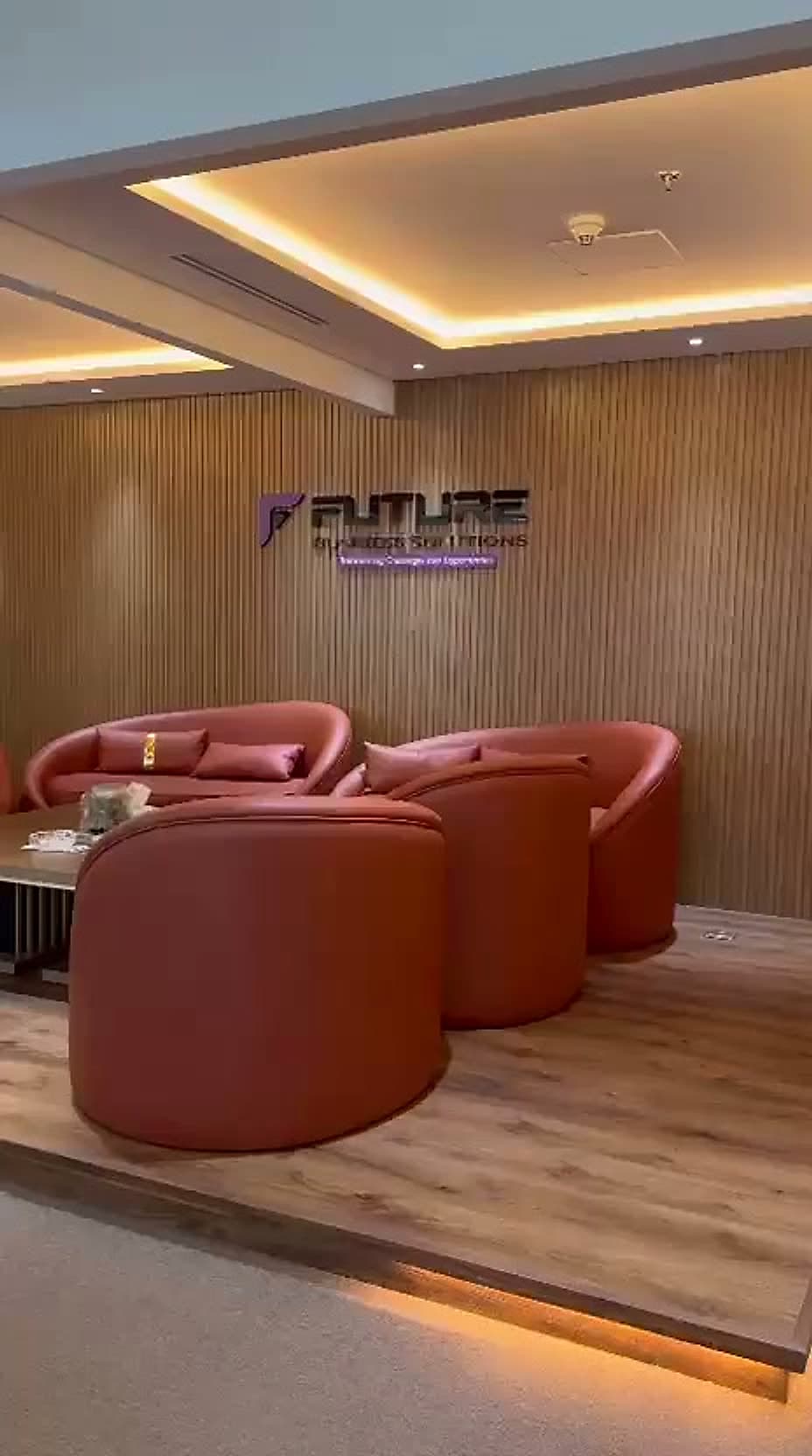 The Future Business Solutions reception lounge, with the branded wall sign above tan leather seating