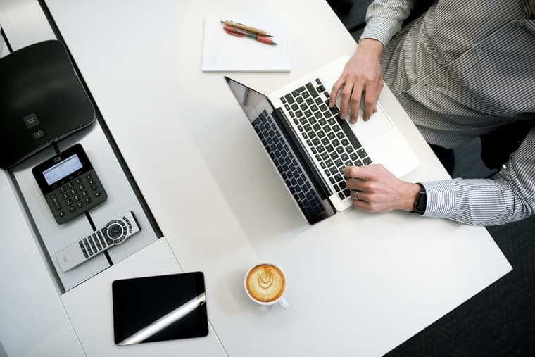 An office desk from above with a laptop, documents and a telephone